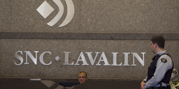 Royal Canadian Mounted Police officer looks at a receptionist at the headquarters of SNC Lavalin in Montreal