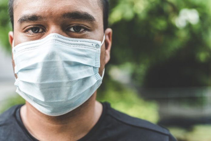 Close-Up Portrait Of Man Wearing Pollution Mask While Standing Against Trees
